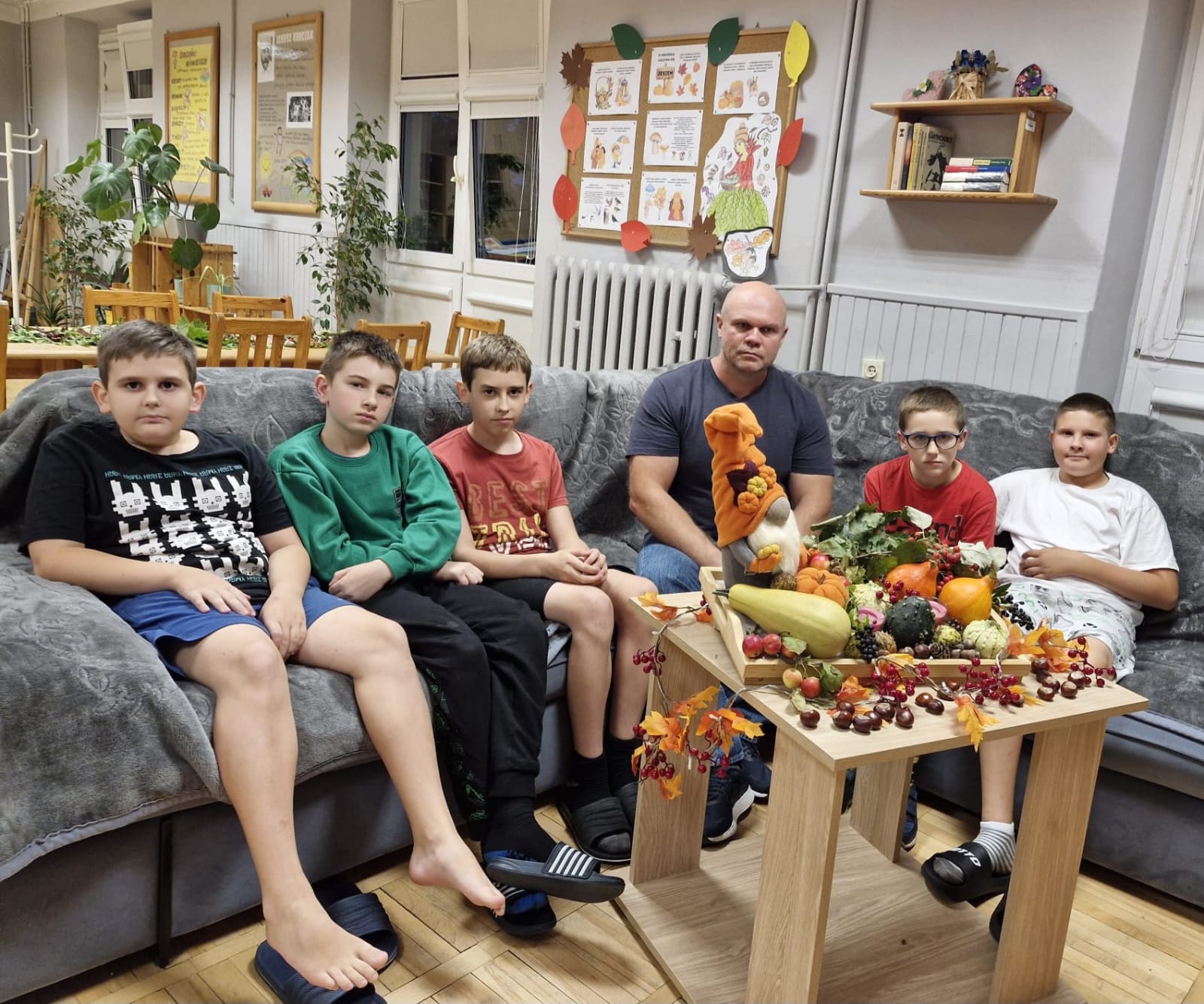 Pięcioro chłopców i wychowawca siedzą przy stoliku z jesiennymi dekoracjami