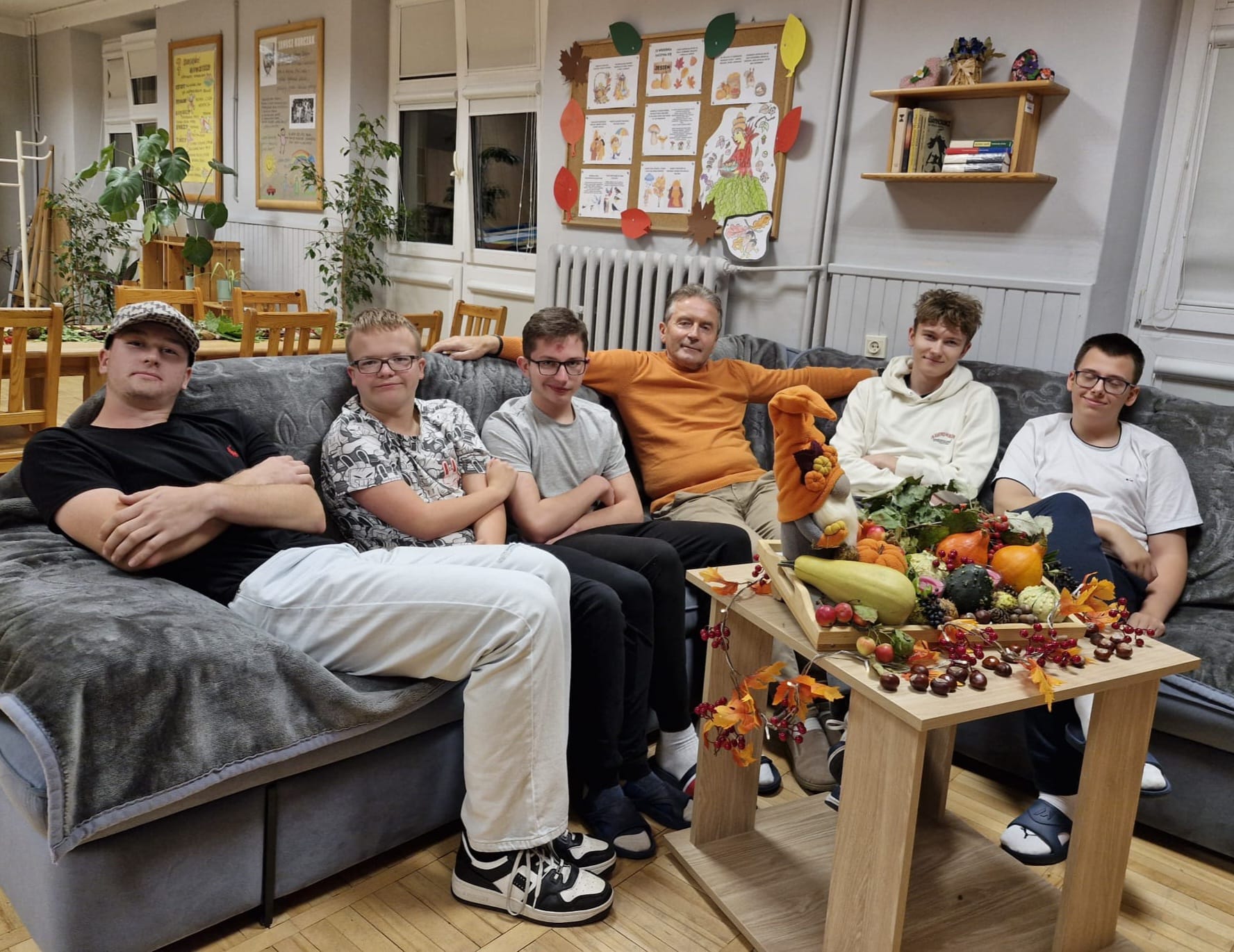 Nastoletni chłopcy i ich wychowawca siedzą na kanapie w świetlicy