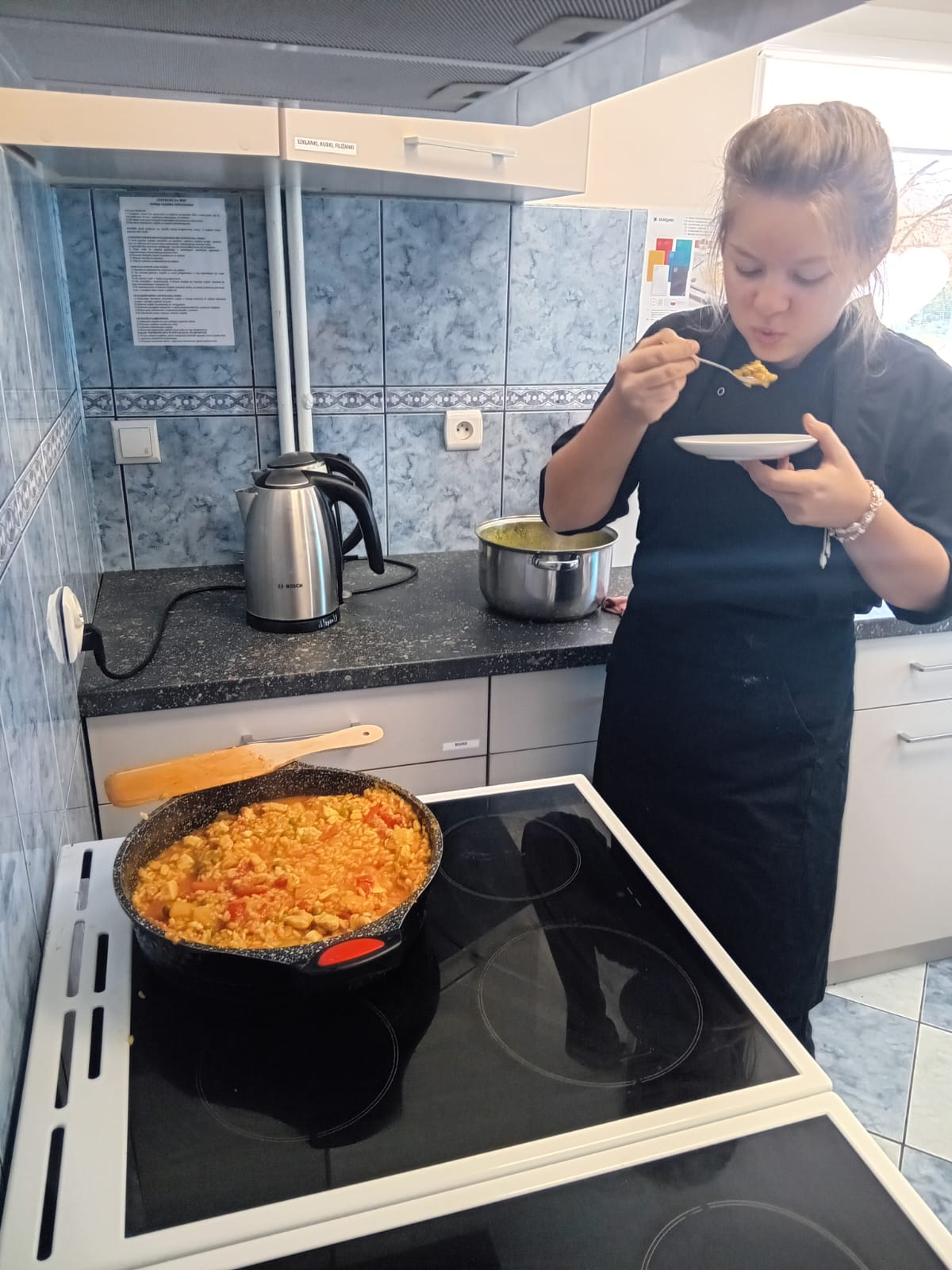 Uczennica próbuje gotową paellę.