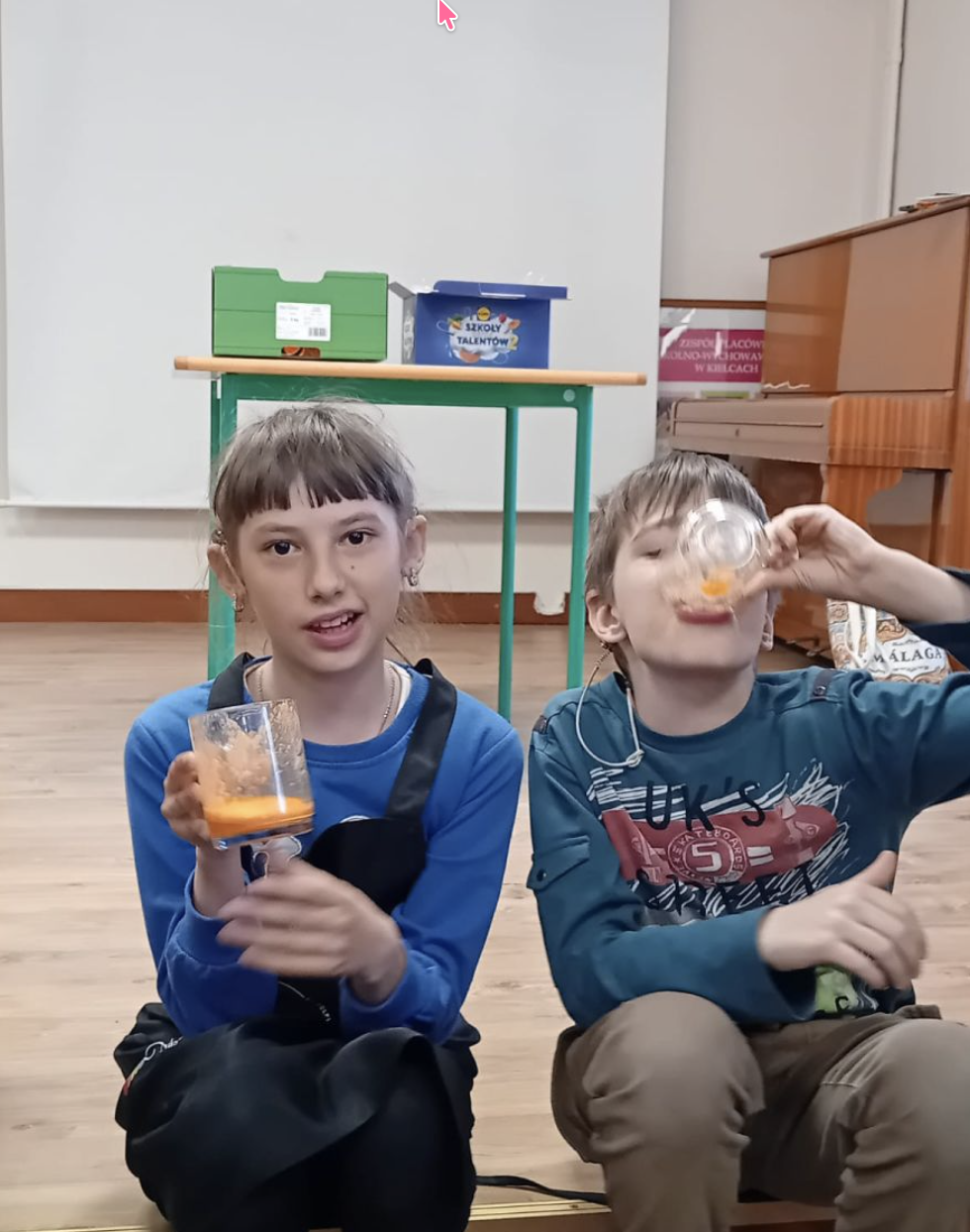 Dziewczyna trzyma szklankę z sokiem, chłopiec pije sok