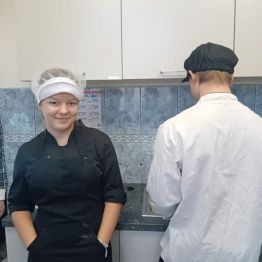 Uczennica i uczeń w fartuchach w pracowni kucharskiej