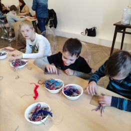 Grupa uczniów samodzielnie tka swoją podkładkę pod kubek.