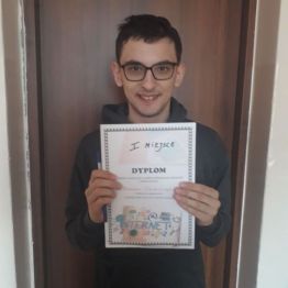 wychowanek trzyma dyplom za udział w konkursie