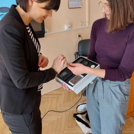 Prowadząca szkolenie prezentuje model implantu słuchowego uczestnikowi. 