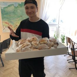 Uczeń trzyma pudełko z pączkami.