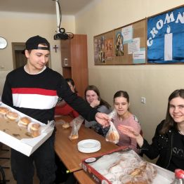 Przedstawiciel Samorządu Uczniowskiego rozdaje pączki.