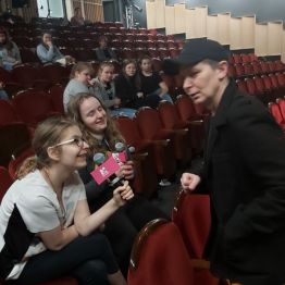 Aktor tłumaczy wychowankom jak korzystać z mikrofonu na scenie.