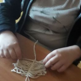 dziewczynka robi makramę "listek" ze sznurków