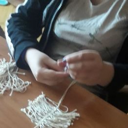 dziewczynka robi makramę "listek" ze sznurków