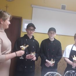 wychowankowie wraz z Panią Dyrektor trzymają w dłoni deser z galaretki, biteej śmietany i owoców