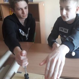 kolejni chłopcy dotykają dłonią kamertony i słysza drgania 