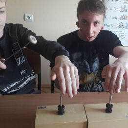 kolejni chłopcy dotykają dłonią kamertony i słysza drgania 