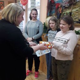 Pani Kierownik Internatu wręcza dyplom dziewczyncę za zajęcie pierwszego miejsca i słodycze