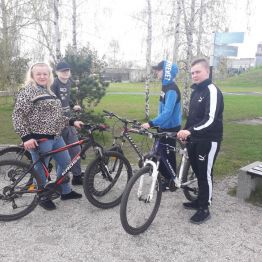 wychowankowie stoją obok rowerów w parku