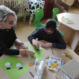 Gosia z wychowawczynią wykonują baranki z płatków kosmetycznych i słomy.
