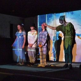 Grupa dzieci na scenie podczas przedstawienia "Piotruś Pan"