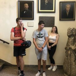 Olek, Patryk i Julia stoją pod portretami twórców związanych z ziemią świętokrzyską.