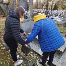 Chłopiec i dziewczynka uporządkowują grób.