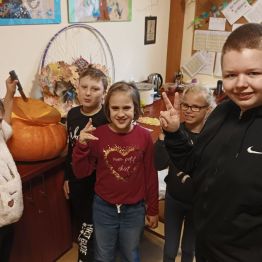 Dzieci prezentują udane odcięcie góry w dyni.