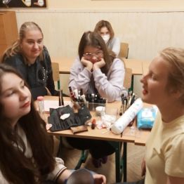 Dziewczynki obserwują wykonywanie makijażu.