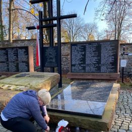 uczennica zapala znicz pod pomnikiem