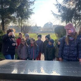 Uczniowie klas I wraz z opiekunami przy pomniku ofiar. 