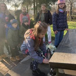 Uczennica z klasy I c składa znicz przy pomniku upamiętniającym ofiary okupacji.