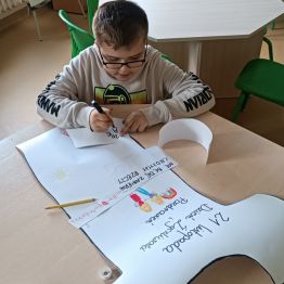 Kacper pisze życzliwe słowa na koszulce.