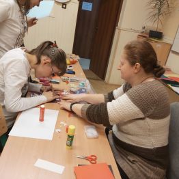 Pani Jola pomagała Mai oklejać kartkę różnymi motywami świątecznymi.