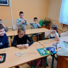 Dzieci z klas 1-3 SP podczas wykonywania wspólnego łańcucha świątecznego.