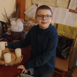 Xsawery przygotowuje świąteczny stroik na plastrach drewna.