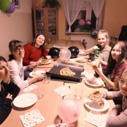 Dziewczyny siedzą przy stole i jedzą pizze