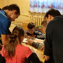 Dziewczyna i chłopcy razem rozwiązują pracę domową.