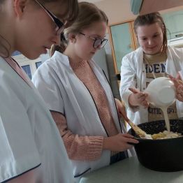 Dziewczynka dodaje sos do pozostałych składników zapiekanki.