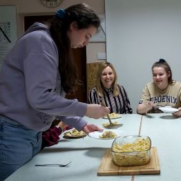 Dziewczynka nakłada gotową zapiekankę na talerze.