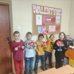 Uczniowie klasy 1 a stojący przed gazetką walentynkową.