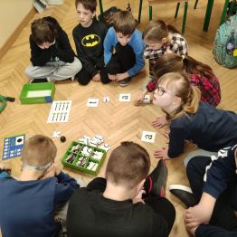 Grupa uczniów klasy 1 a, 1 c układająca puzzle- drogę dla ozobota. 