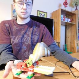 chłopiec prezentuje swoja prace z klocków lego