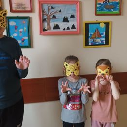 Dzieci w maskach karnawałowych naśladują ruchy zwierząt.