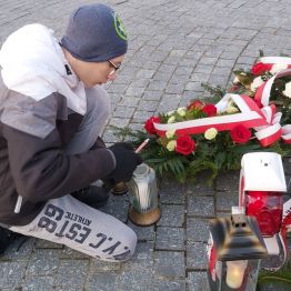 Chłopiec zapala znicz, który przynieśliśmy pod pomnik.