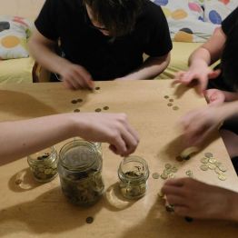 dzieci segregują monety do słoiczków