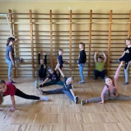 Dzieci wykonują różne pozycje gimnastyczne.