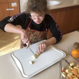 Hania siedzi przy stole i kroi gruszkę.