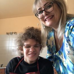 Hania siedzi, pani Basia stoi po jej lewej stronie. Na stole leży gotowy deser owocowy.