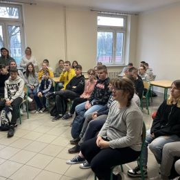 Liczna grupa uczniów siedzi na krzesłach