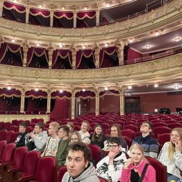 Uczniowie siedzący na teatralnej widowni. W tle loże.