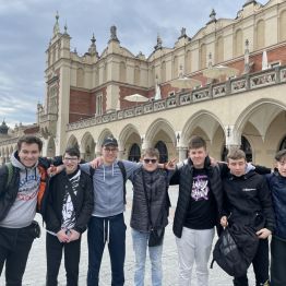 Grupa chłopców trzymających się za ramiona. W tle Sukiennice.