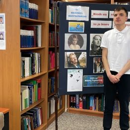 Uczeń recytuje wiersz. W tle tablica ze zdjęciami Wisławy Szymborskiej i regały z książkami.