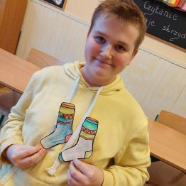 Uczeń pokazuje swoje dzieło  - pokolorowane skarpetki