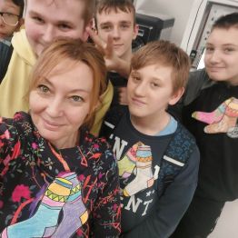 Uczniowie klasy 7b z wychowawcą i przyjętymi papierowymi skarpetkach w różnych kolorach